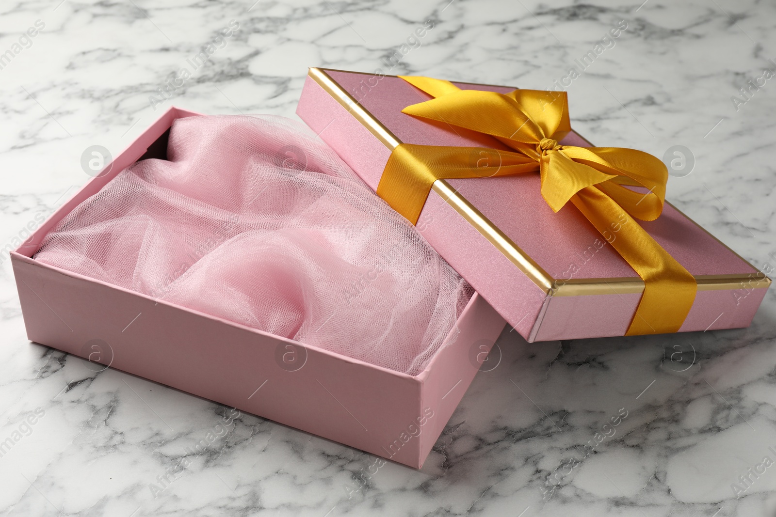 Photo of Opened gift box with beautiful lid on white marble table, closeup