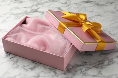 Photo of Opened gift box with beautiful lid on white marble table, closeup
