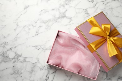 Photo of Opened gift box with beautiful lid on white marble table, top view. Space for text