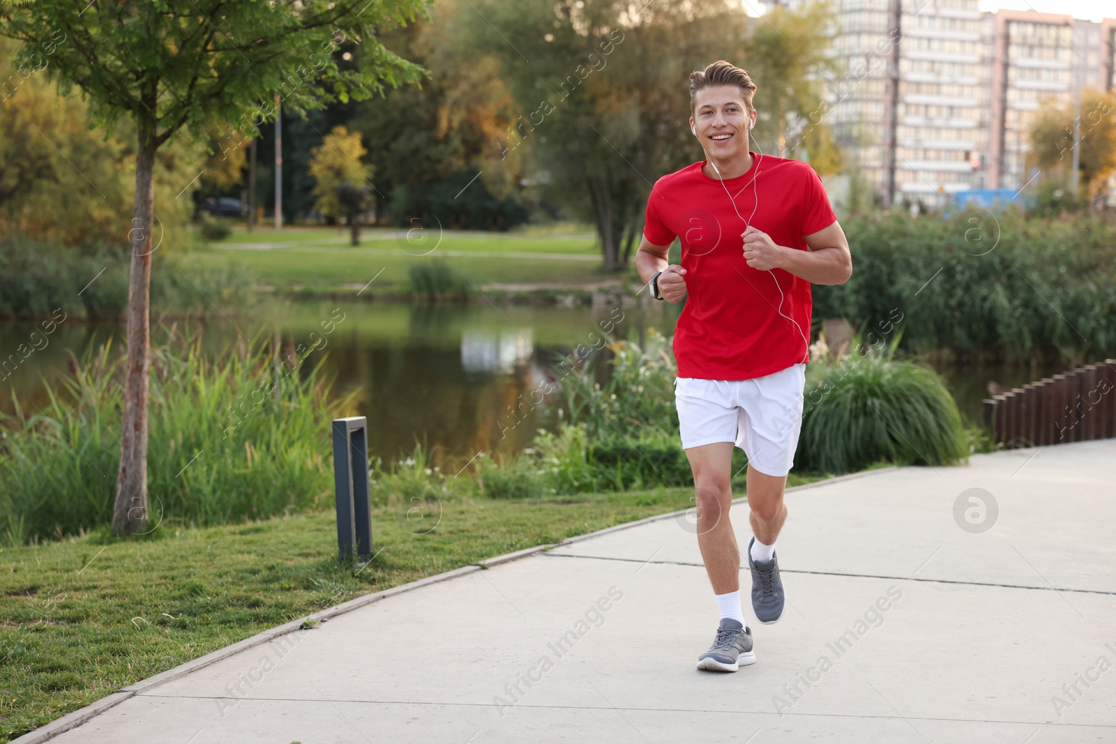 Photo of Happy man in earphones running outdoors, space for text
