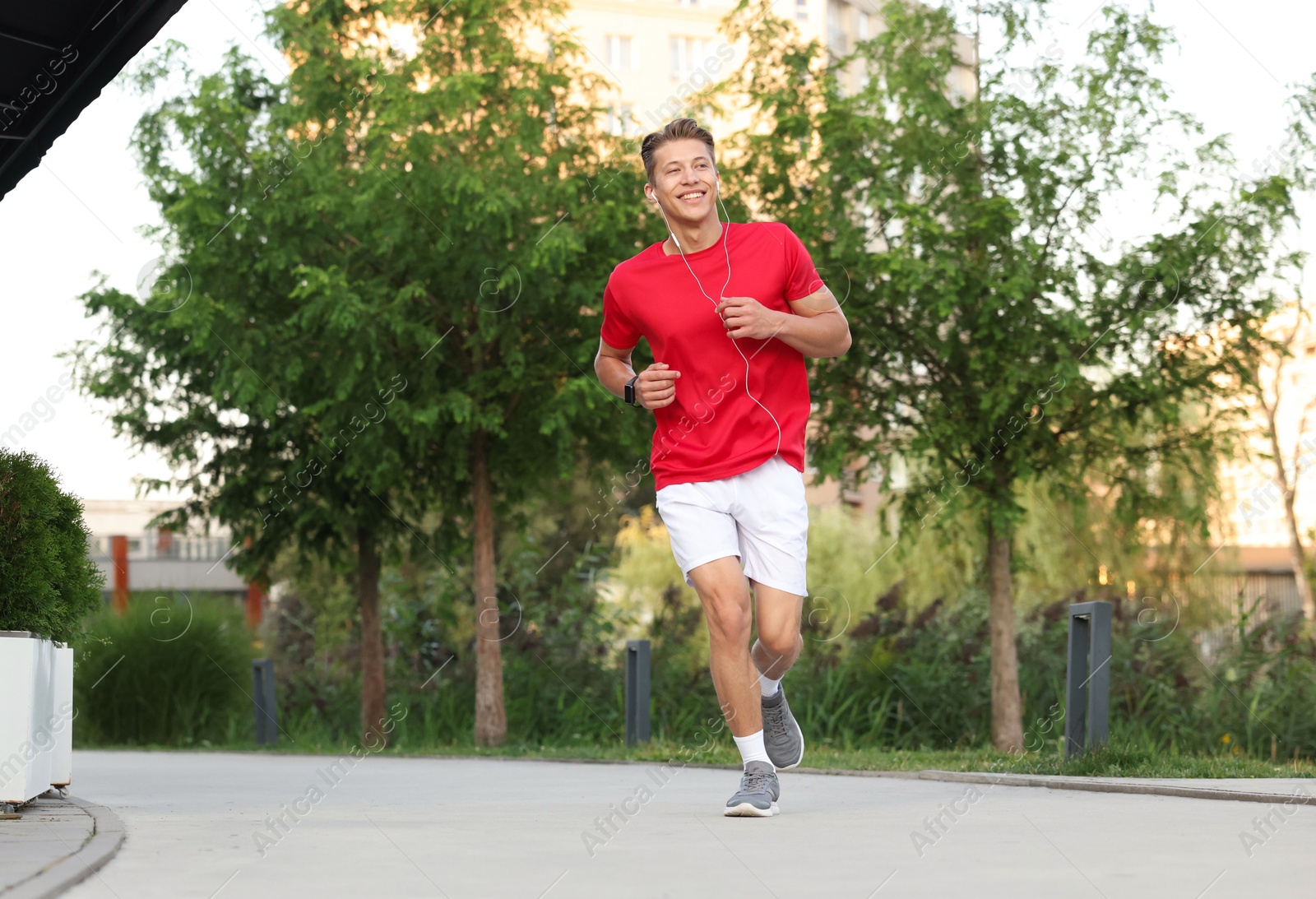Photo of Happy man in earphones running outdoors, low angle view