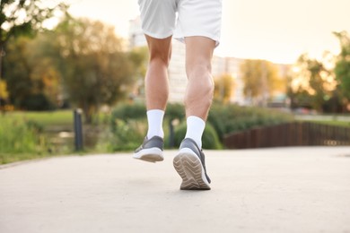 Photo of Athletic man in sneakers running outdoors, closeup