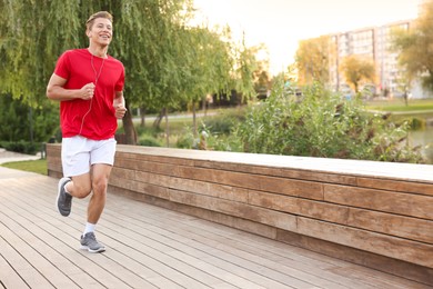 Photo of Happy man in earphones running on city street
