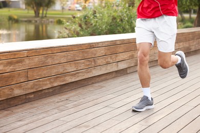 Photo of Athletic man in sportswear running outdoors, closeup