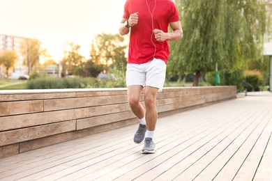 Photo of Athletic man in sportswear running outdoors, closeup