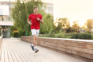 Photo of Happy man in earphones running on city street