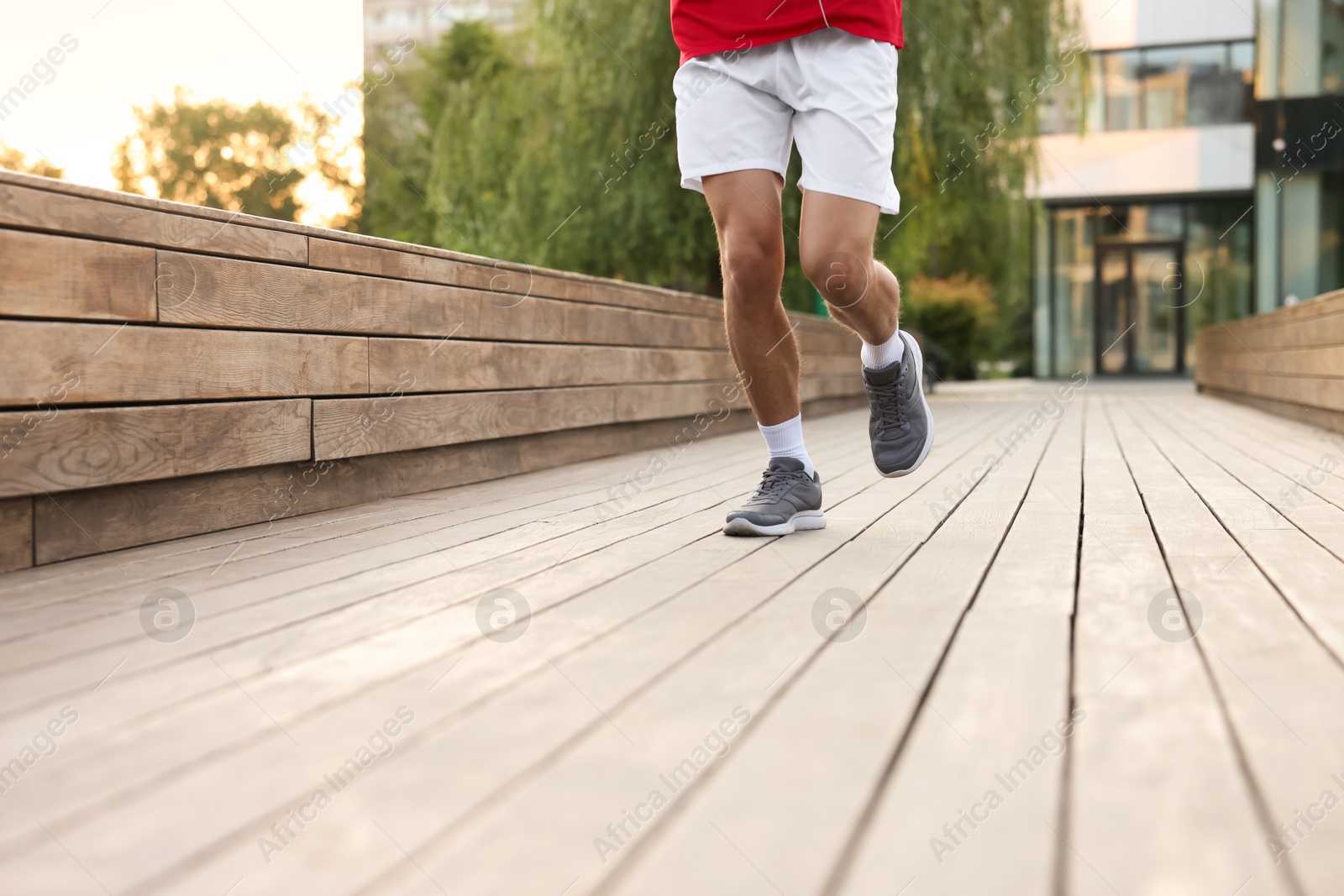 Photo of Athletic man in sneakers running outdoors, closeup