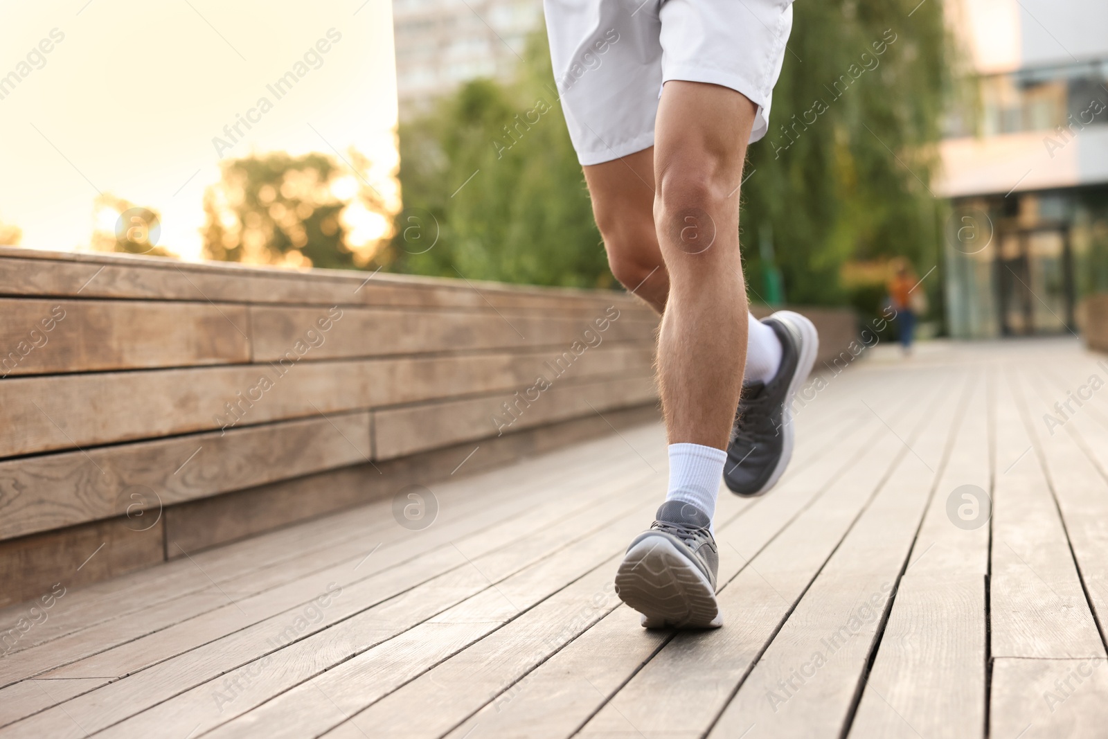 Photo of Athletic man in sneakers running outdoors, closeup