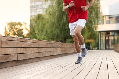 Photo of Athletic man in sneakers running outdoors, closeup