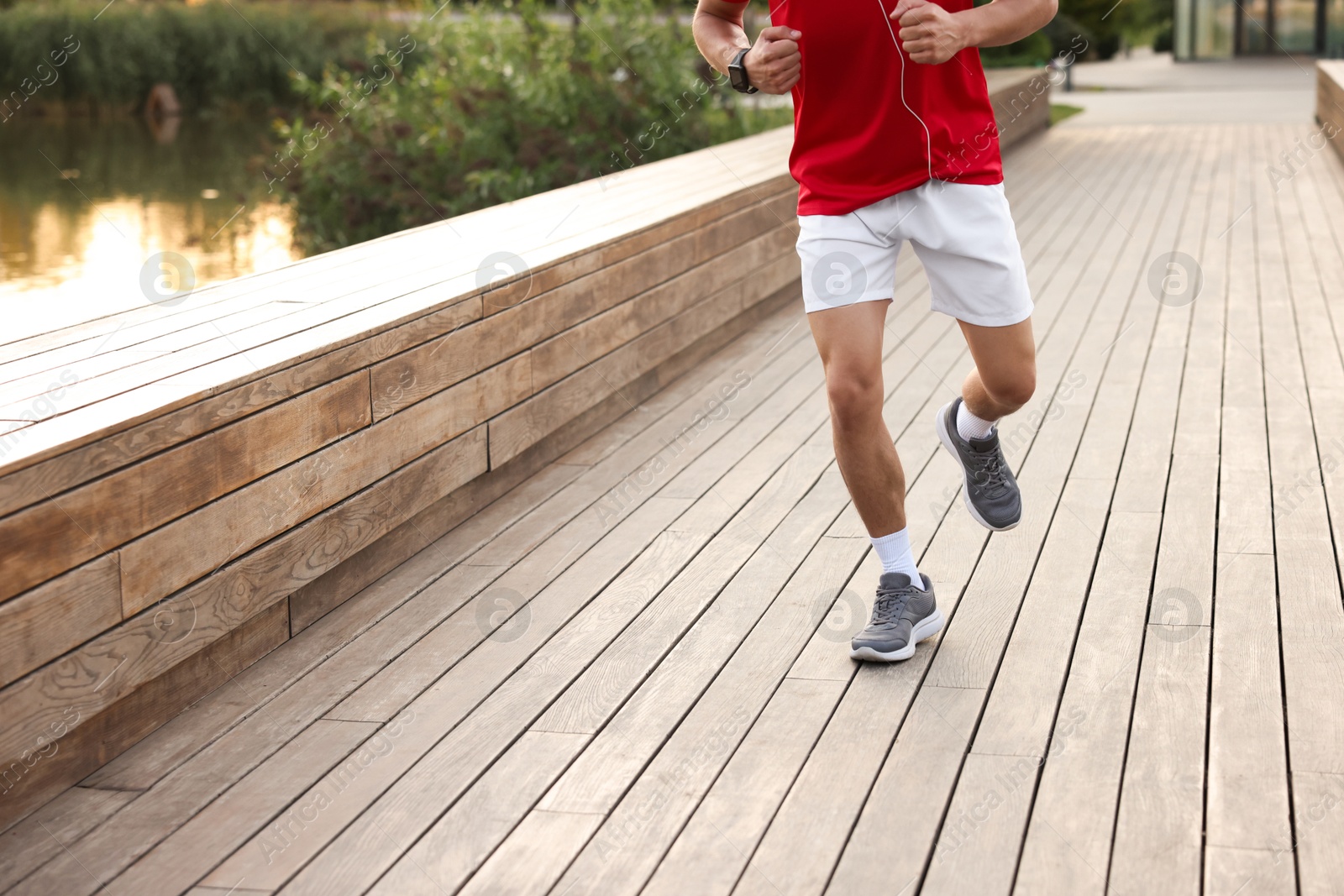 Photo of Athletic man in sneakers running outdoors, closeup
