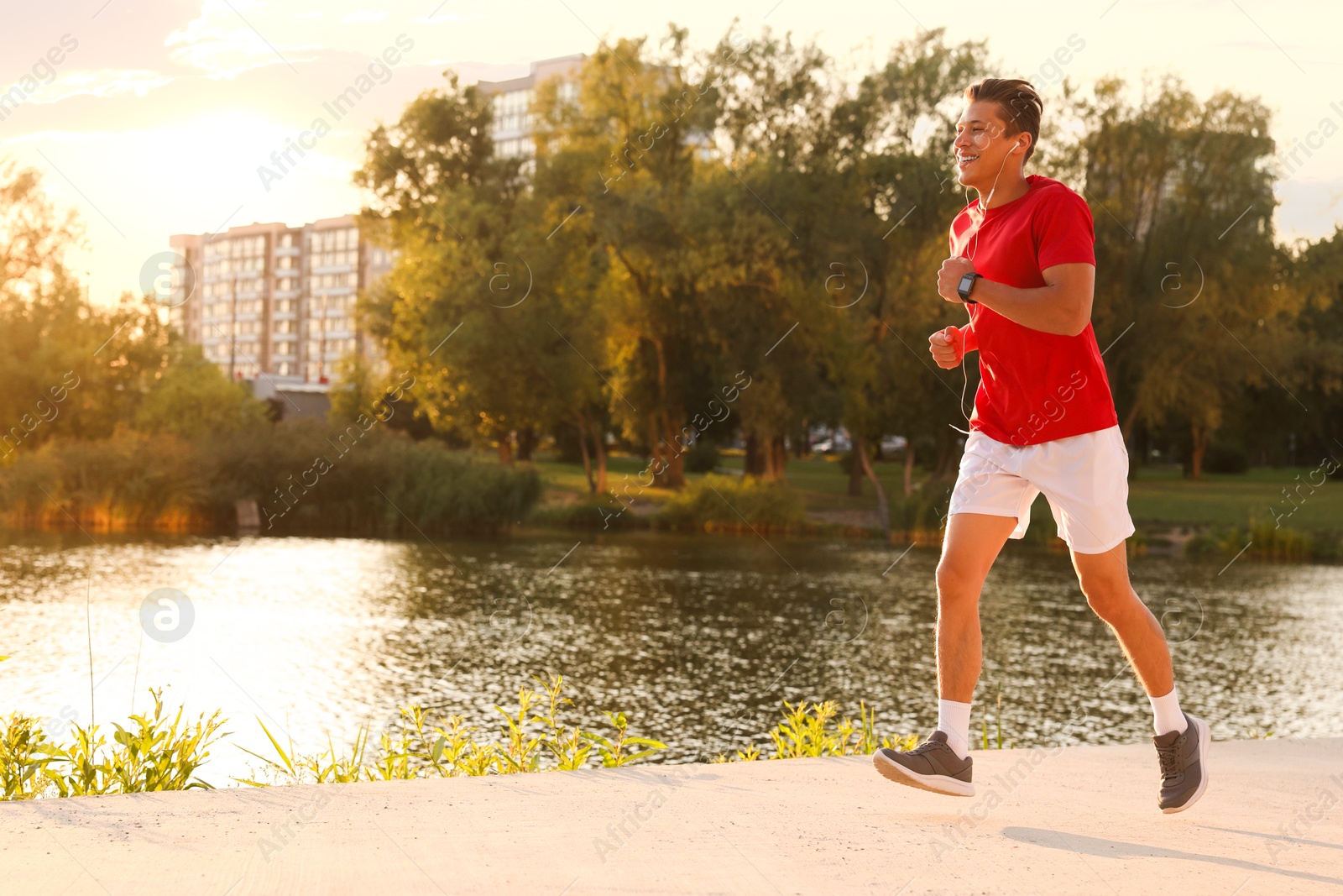 Photo of Athletic man running near lake in park, space for text