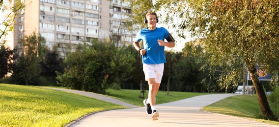 Photo of Happy man with headphones running in park