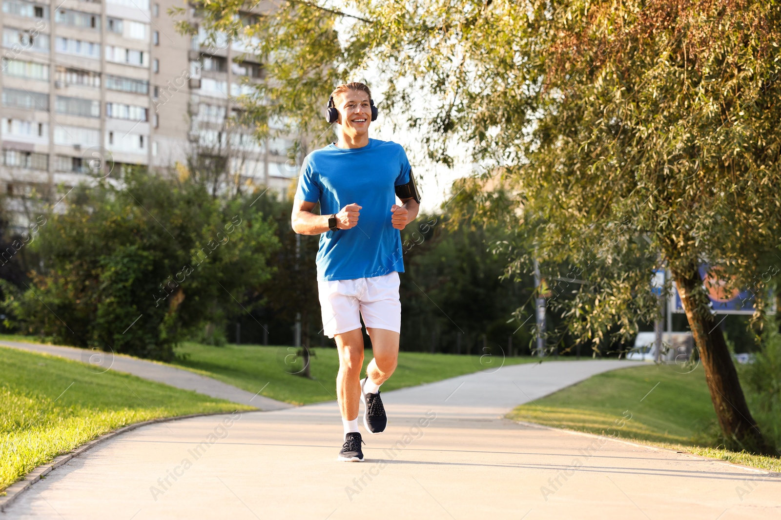 Photo of Happy man with headphones running in park
