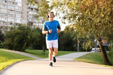 Photo of Happy man with headphones running in park