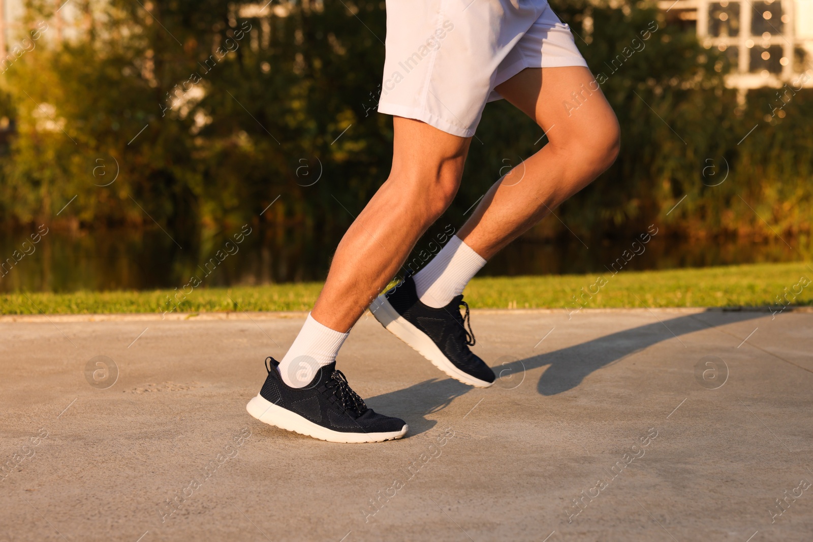Man running near lake in park on sunny day, closeup Photo of Man running near lake in park on sunny day, closeup