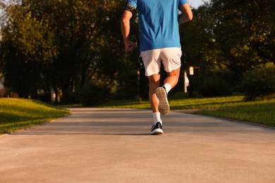 Photo of Man running in park on sunny day, closeup. Space for text