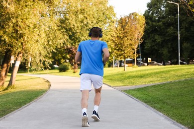 Photo of Man running in park on sunny day, back view