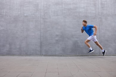 Photo of Man running near building on city street, space for text