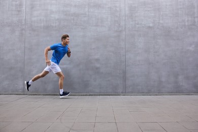 Photo of Man running near building on city street, space for text