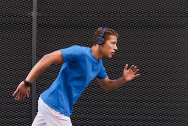 Photo of Man in headphones running near building on city street
