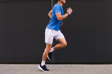 Photo of Man running near building on city street, closeup