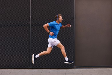 Photo of Man in headphones running near building on city street