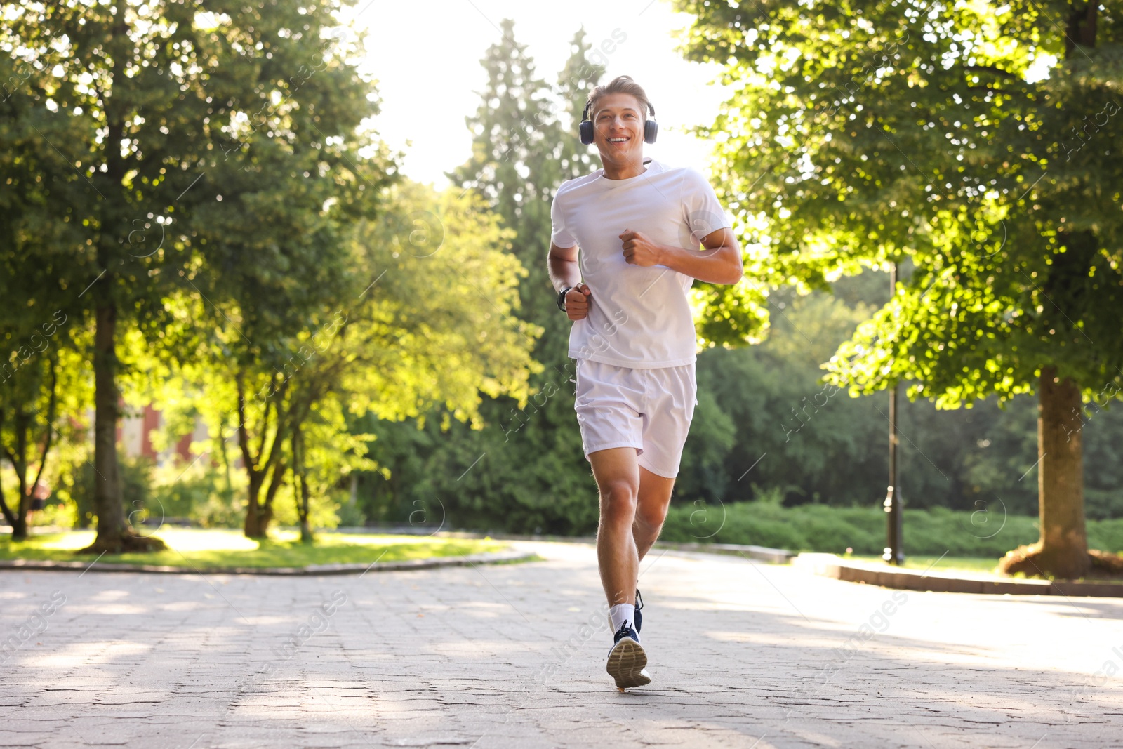 Happy man with headphones running in park Photo of Happy man with headphones running in park