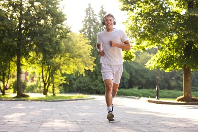 Photo of Happy man with headphones running in park