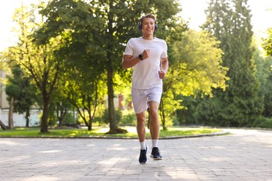 Photo of Happy man with headphones running in park