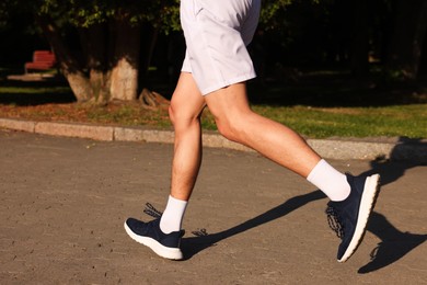 Photo of Man in stylish sneakers outdoors on sunny day, closeup