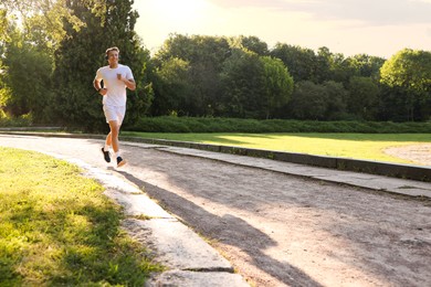 Photo of Happy man with headphones running in park
