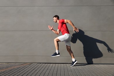 Photo of Man in sportswear running near building outdoors, space for text