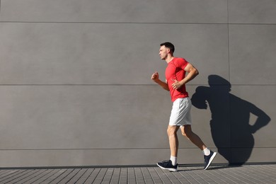 Photo of Man in sportswear running near building outdoors, space for text