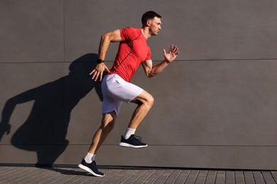 Photo of Man in sportswear running near building outdoors, space for text