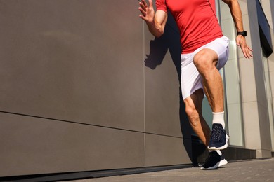 Photo of Man in sportswear running near building outdoors, closeup. Space for text