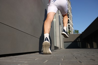 Photo of Man in sportswear running near building outdoors, closeup