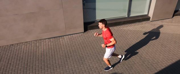 Photo of Man in sportswear running near building outdoors, above view. Space for text