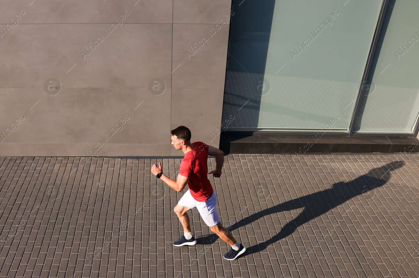 Photo of Man in sportswear running near building outdoors, above view