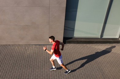 Photo of Man in sportswear running near building outdoors, above view