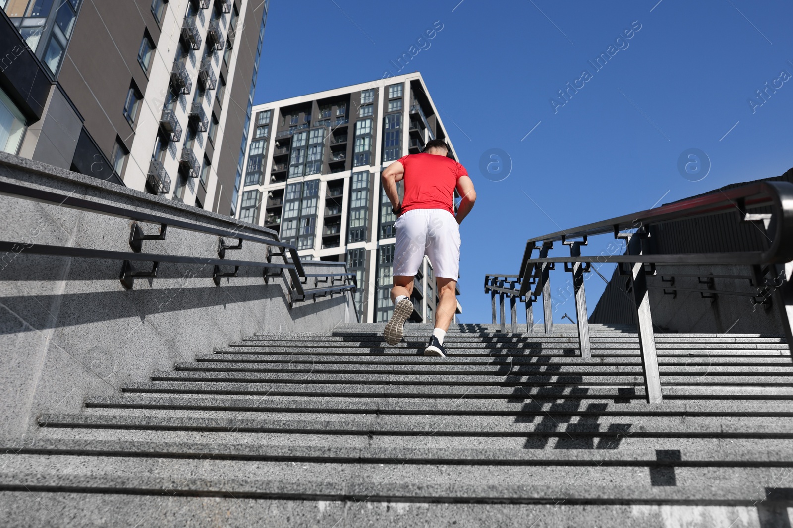 Man in sportswear running up on stairs outdoors, low angle view Photo of Man in sportswear running up on stairs outdoors, low angle view