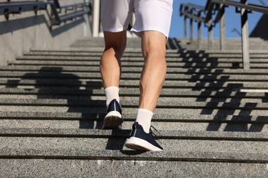 Photo of Man in sneakers running up on stairs outdoors, closeup