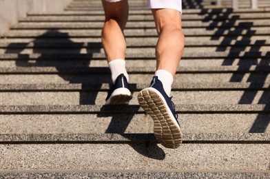 Photo of Man in sneakers running up on stairs outdoors, closeup