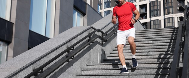 Photo of Man in sportswear running down on stairs outdoors, closeup