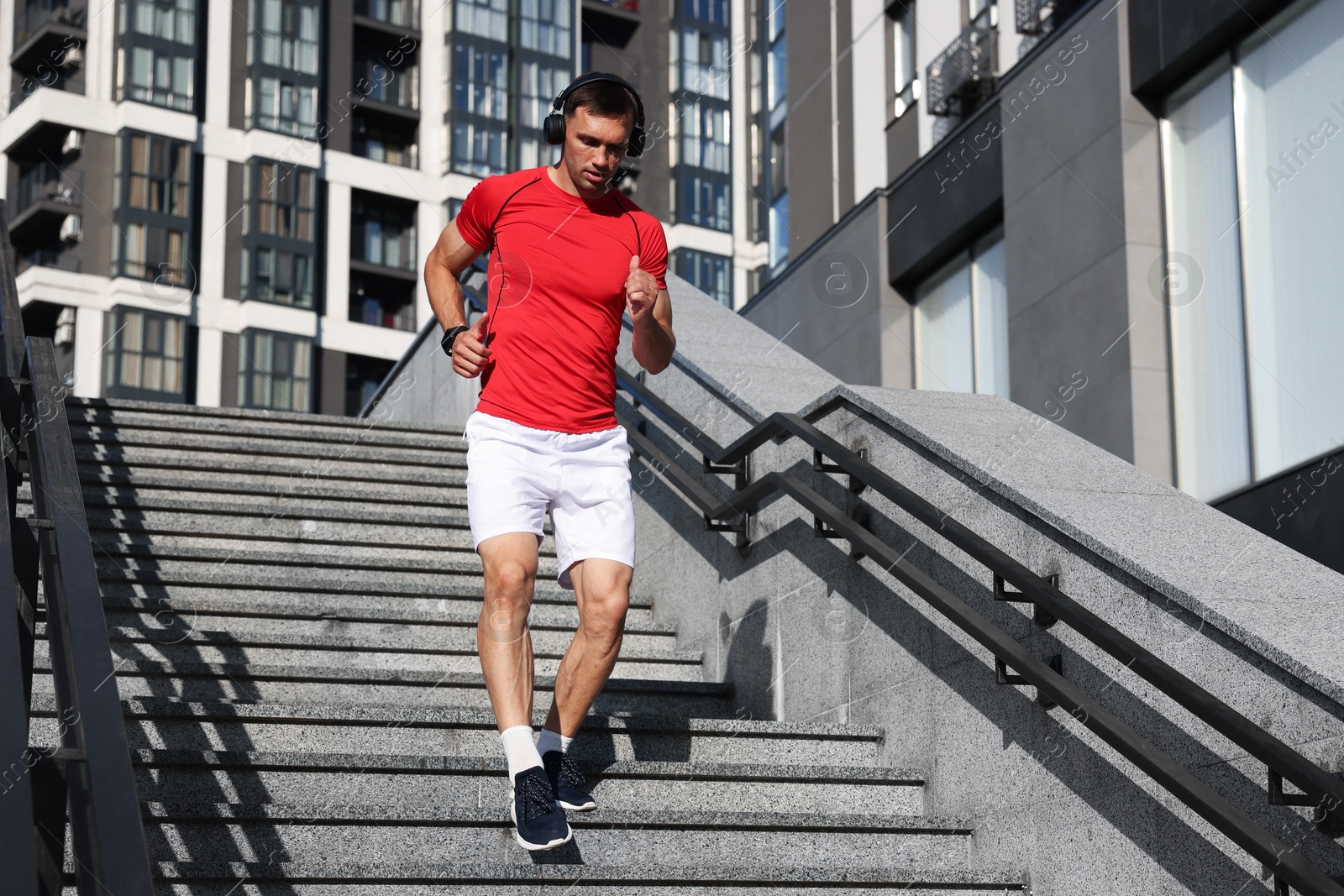 Photo of Man in sportswear running down on stairs outdoors