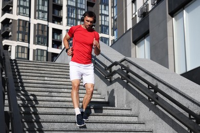 Photo of Man in sportswear running down on stairs outdoors