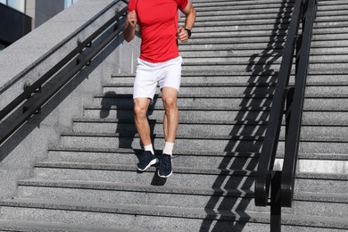 Photo of Man in sportswear running down on stairs outdoors, closeup