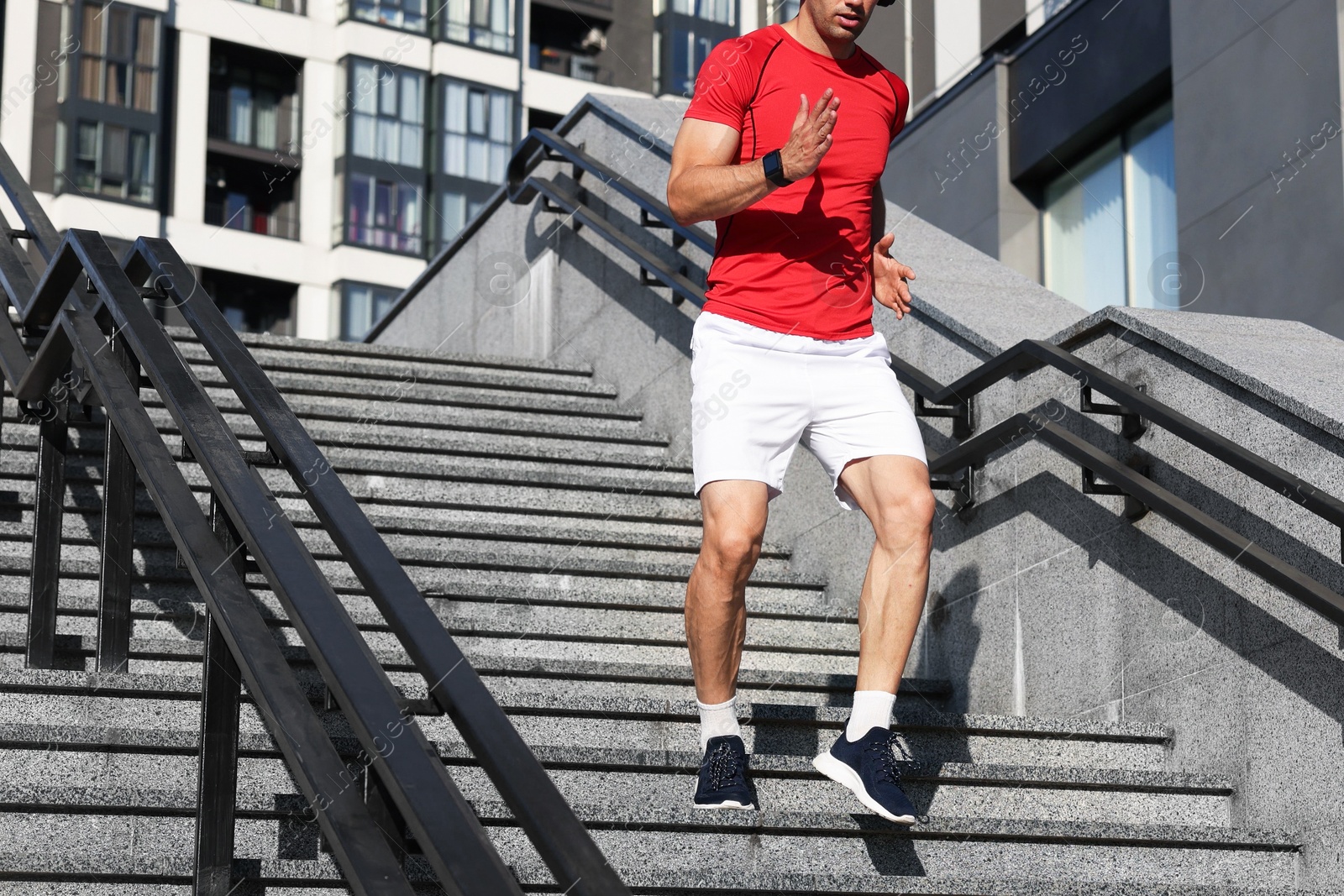 Photo of Man in sportswear running down on stairs outdoors, closeup