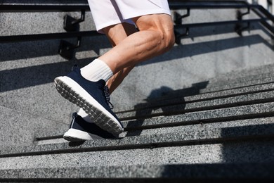 Photo of Man in sportswear running up on stairs outdoors, low angle view