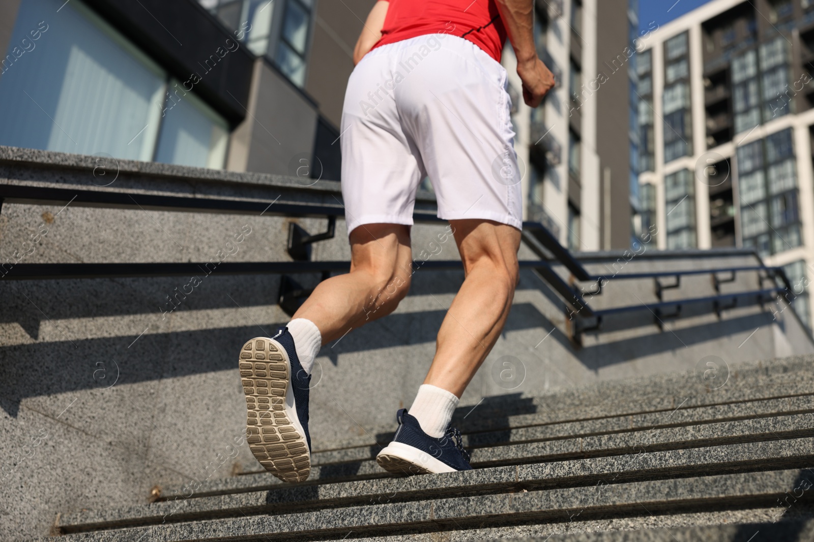 Photo of Man in sportswear running up on stairs outdoors, low angle view