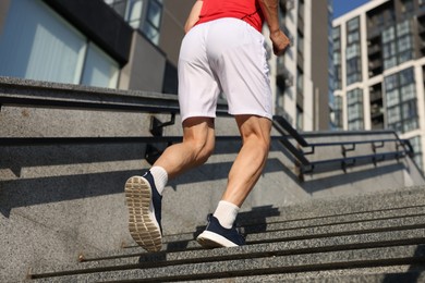 Photo of Man in sportswear running up on stairs outdoors, low angle view